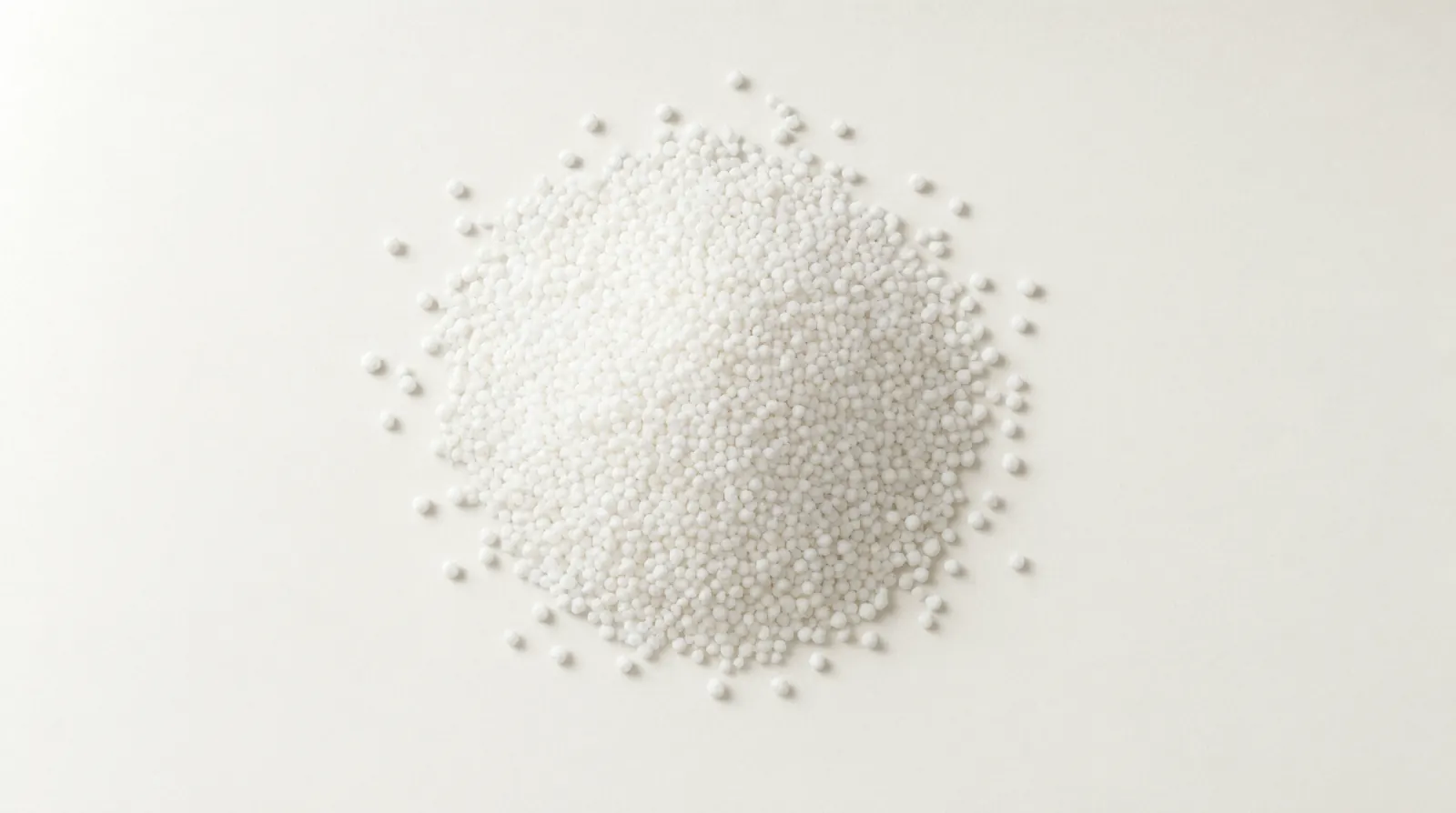 A heap of white prilled urea, near-spherical granules, photographed from above.